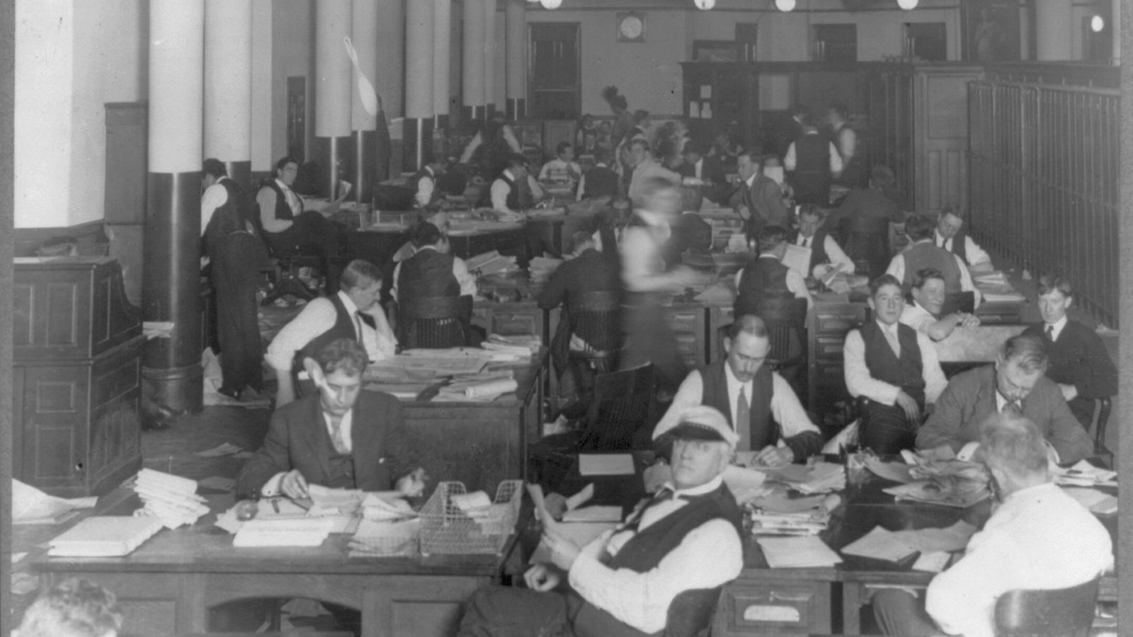 Reporters and editors writing at their desks in the newsroom of the New York World newspaper
