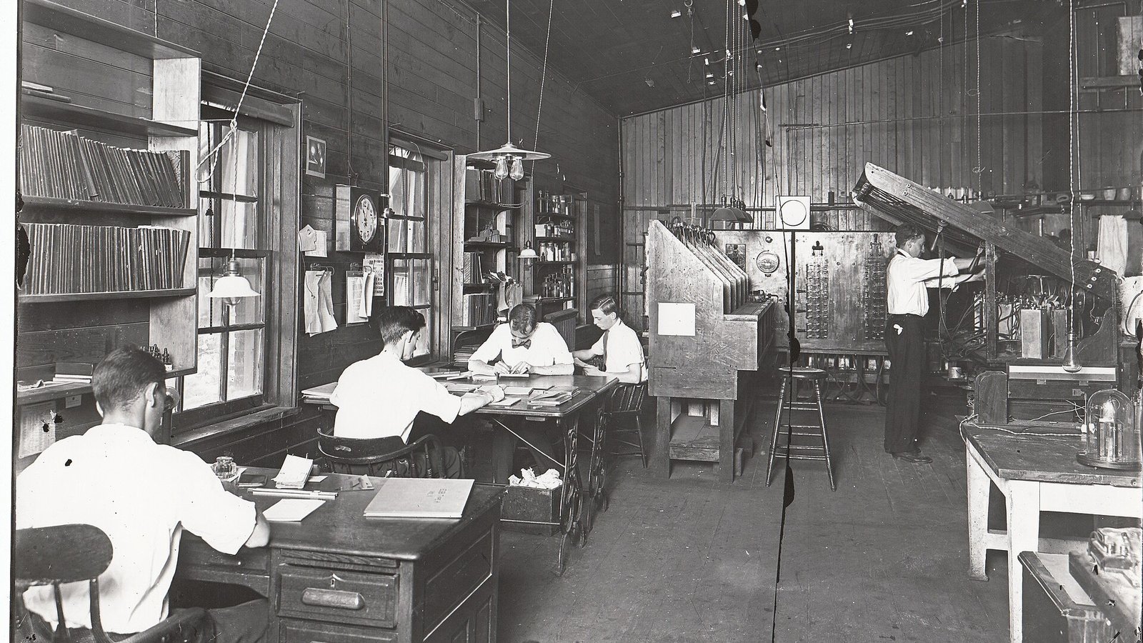 A drawing office where engineers and draughtsmen work on technical drawings at long drafting tables