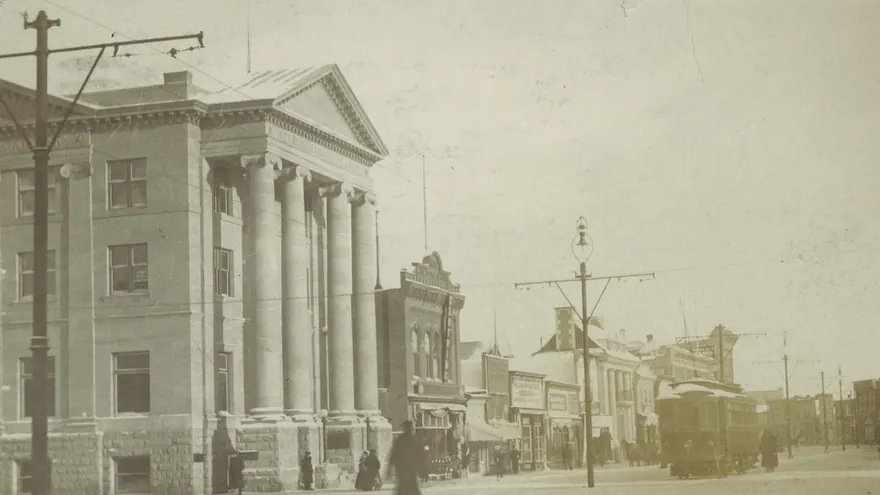 1910 dolaylarında Edmonton'da Jasper Caddesi: solda sütunlu taş bir bina, karlı caddede bir tramvay ve yayalar, uzaklara uzanan dükkân cepheleri