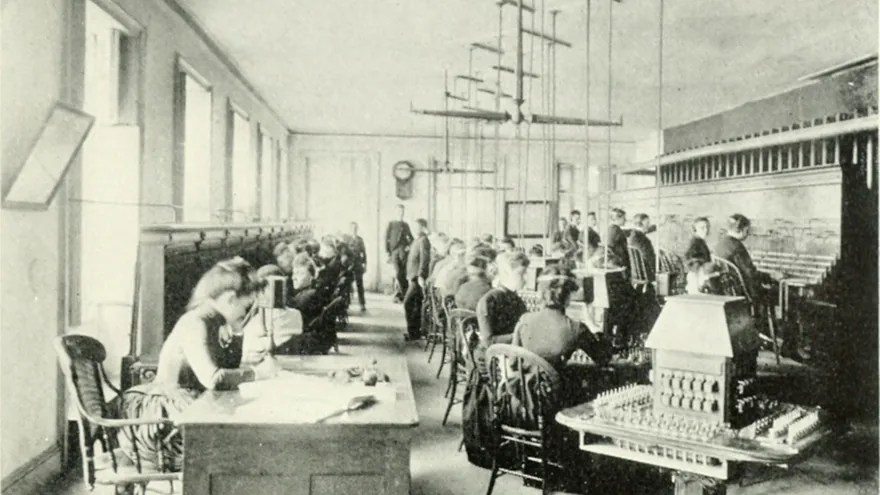 1880'lerde New York'ta bir telefon santrali: uzun bir salonda sıra sıra oturan genç kadın ve oğlan operatörler ile ön planda bir anahtarlama panosu