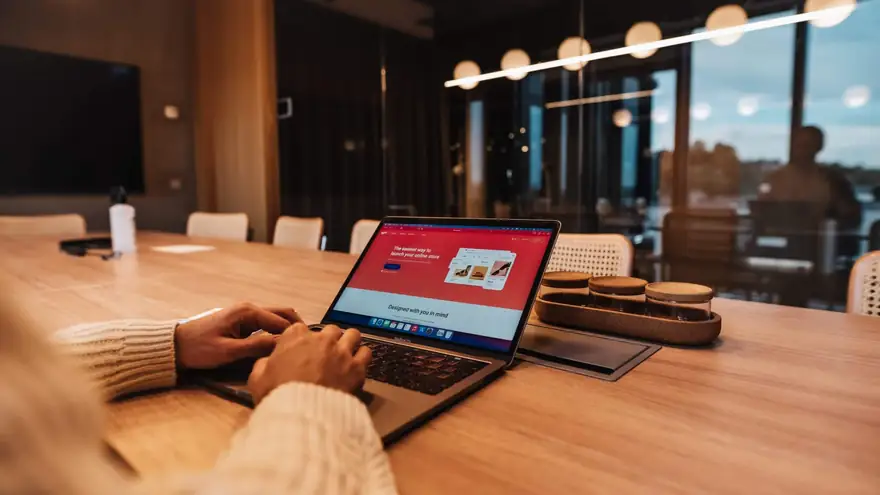Ahşap masada açık dizüstü bilgisayarda online mağaza sayfasına bakan kişi